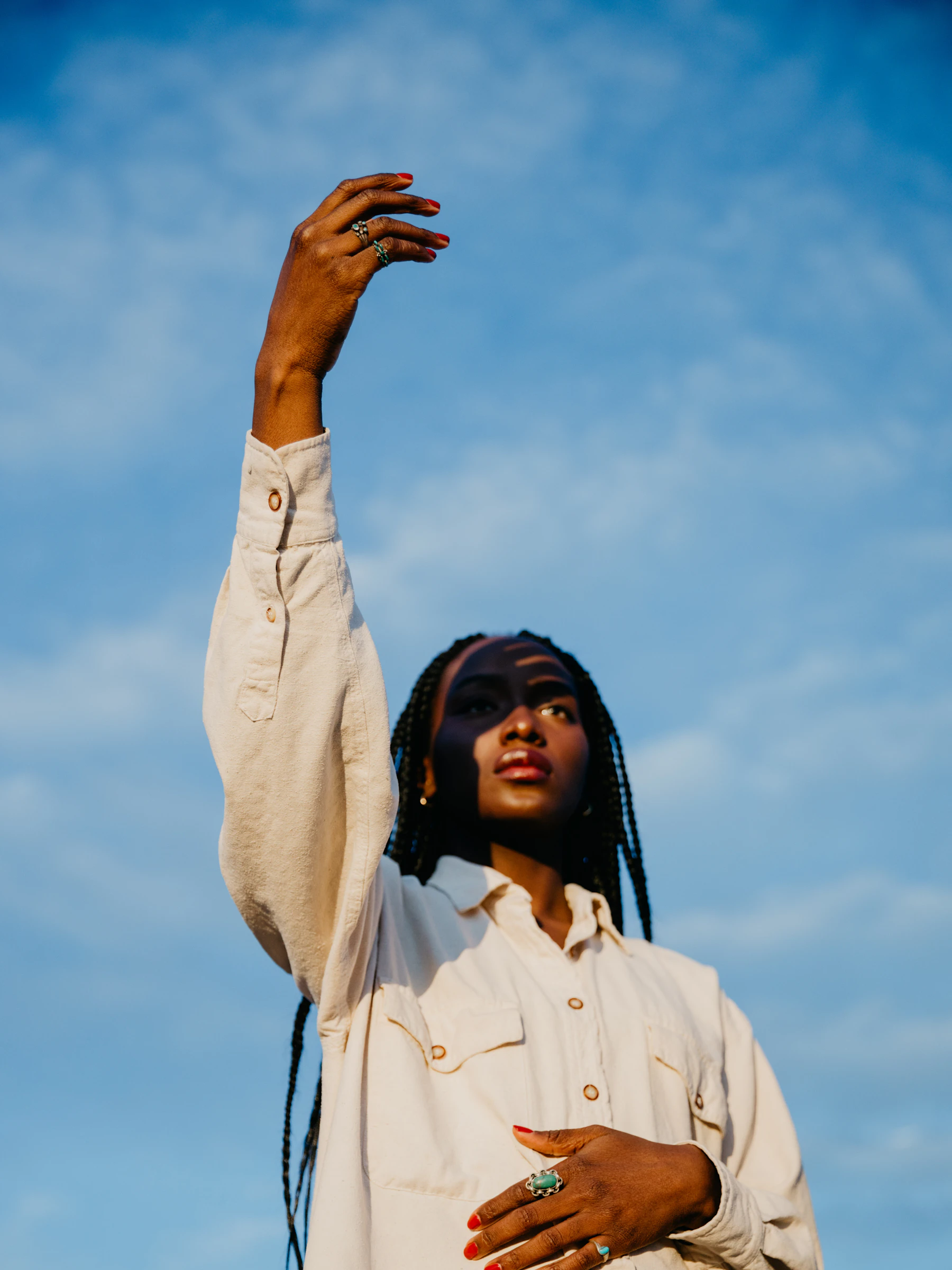 A woman reaching up towards a blue sky