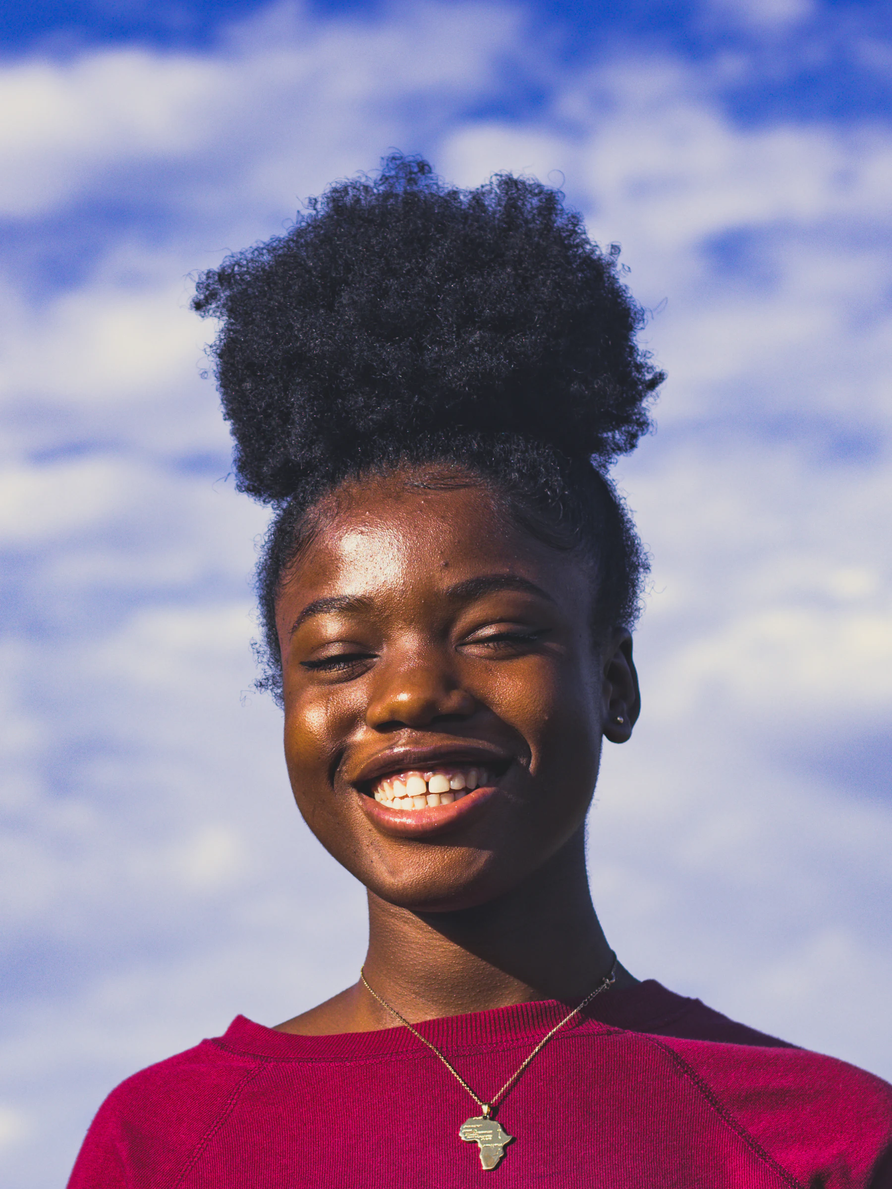 A woman laughing under a cloudy sky